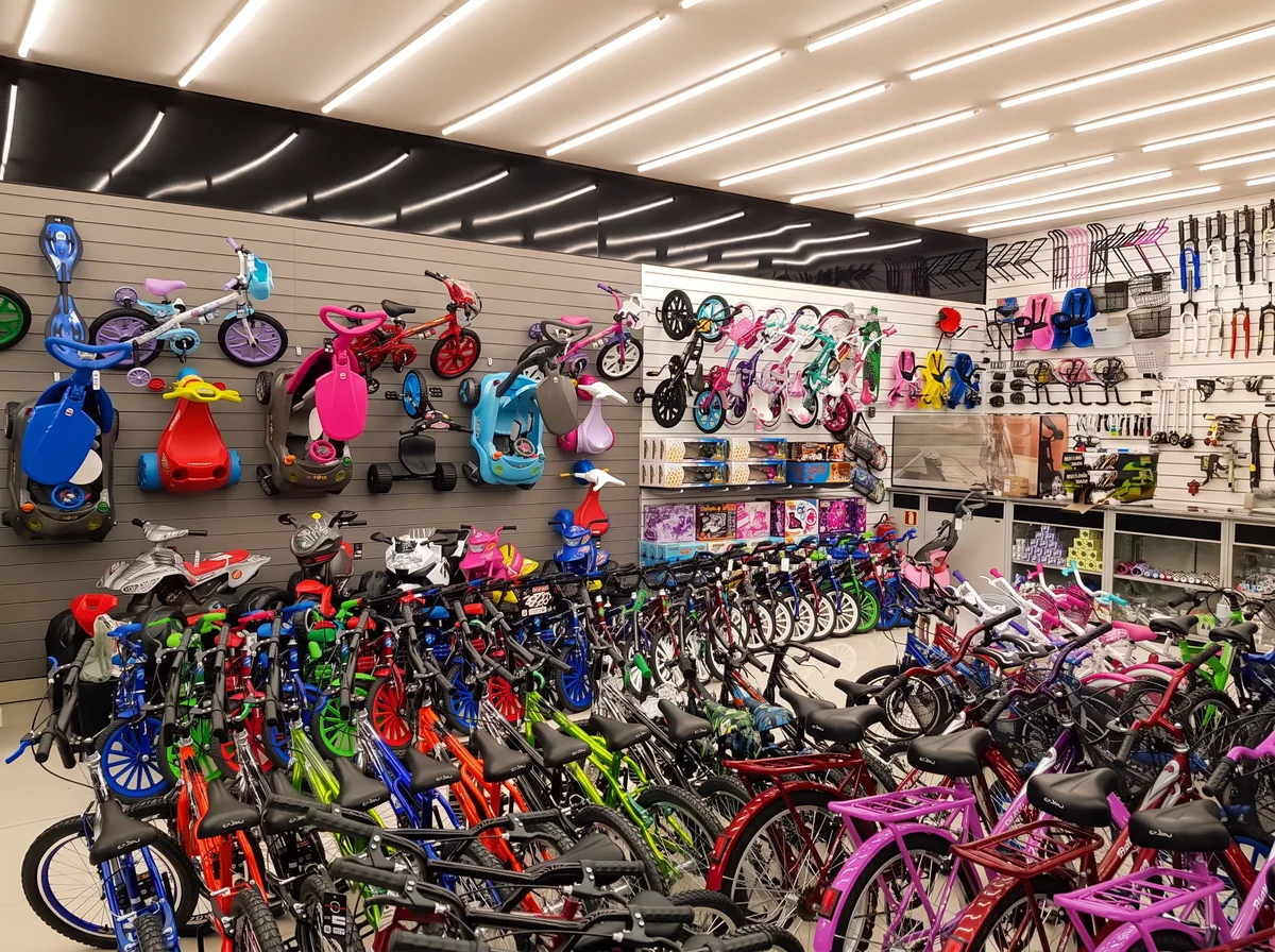 Interior de uma loja Marrafa's: parede com bicicletas infantis e brinquedos elétricos e fileiras de bicicletas coloridas no chão